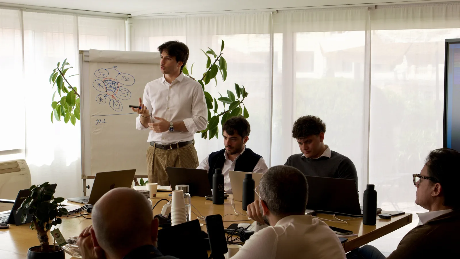 A flip chart and open laptops around the table during training